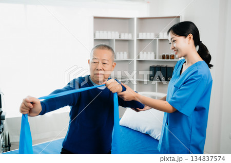Asian physiotherapist helping elderly man patient stretching arm during exercise correct with dumbbell in hand during training hand with patient Back problems Asian physiotherapist helping elderly man patient stretching arm during exercise correct with dumbbell in hand during training hand with patient Back problems 134837574