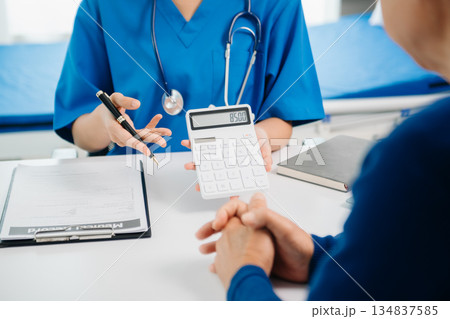 Healthcare costs and fees concept.Hand of smart doctor used a calculator and smartphone, tablet for medical costs at hospital 134837585