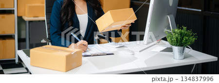 Businesswoman handling packaging and logistics in a modern workspace, managing e-commerce orders efficiently 134837996