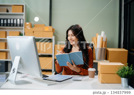 Businesswoman handling packaging and logistics in a modern workspace, managing e-commerce orders efficiently 134837999