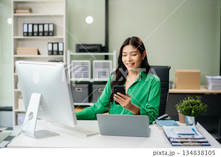 Asian woman using laptop and tablet while sitting at her working place. Concentrated 134838105