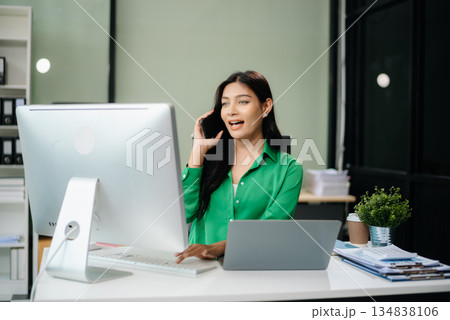 Asian woman using laptop and tablet while sitting at her working place. Concentrated 134838106