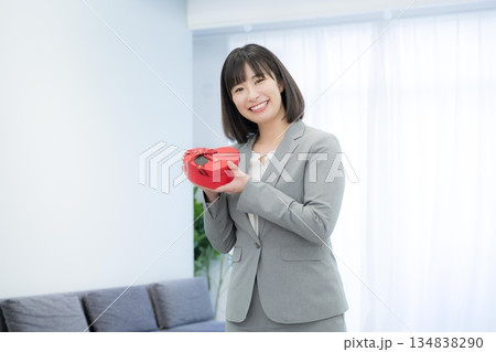 ハートのチョコやプレゼント持つビジネスウーマン 顧客満足度や贈り物などのイメージ ハートのチョコやプレゼント持つビジネスウーマン 顧客満足度や贈り物などのイメージ 134838290