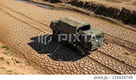 Military Truck Driving On Cracked Earth Under Bright Sunlight Creating Shadow Military Truck Driving On Cracked Earth Under Bright Sunlight Creating Shadow 134838749