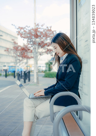 バス停でパソコンを使う日本人女子大学生 134839023