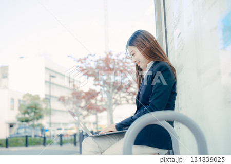 バス停でパソコンを使う日本人女子大学生 134839025