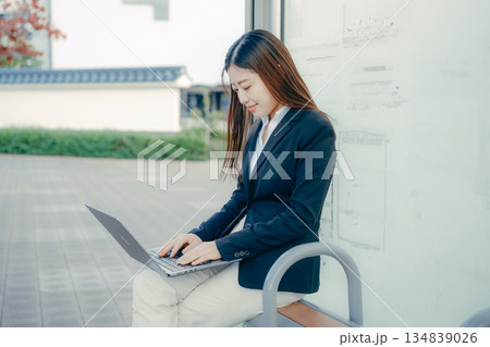バス停でパソコンを使う日本人女子大学生 バス停でパソコンを使う日本人女子大学生 134839026