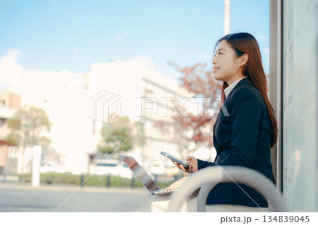 バス停でパソコンとスマホを使う日本人女子大学生 134839045