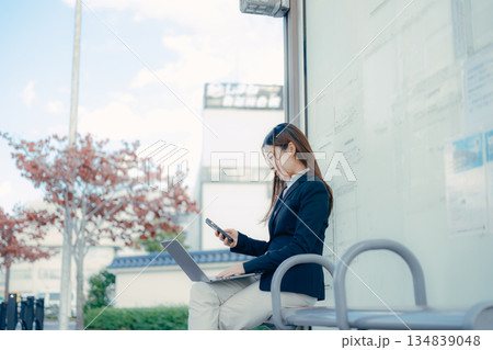 バス停でパソコンとスマホを使う日本人女子大学生 バス停でパソコンとスマホを使う日本人女子大学生 134839048