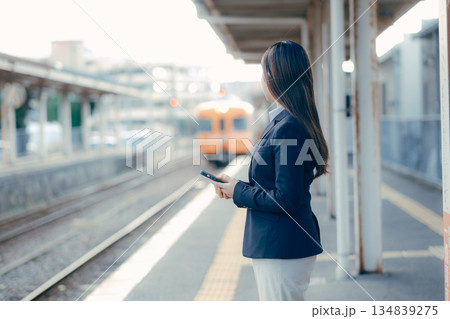 駅のホームでスマホを手に電車を待つ日本人女子大学生 駅のホームでスマホを手に電車を待つ日本人女子大学生 134839275