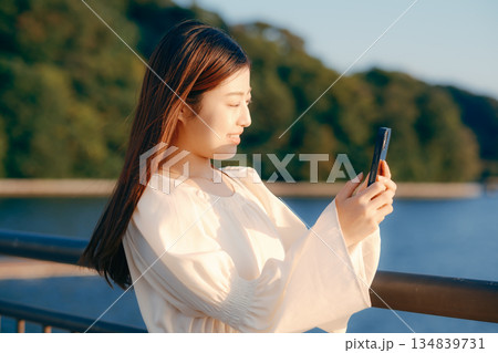 海を背景に堤防でスマホを見る日本人女性 134839731