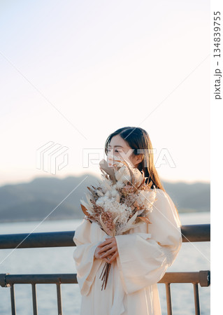 海を背景にドライフラワーを持って佇む日本人女性 134839755
