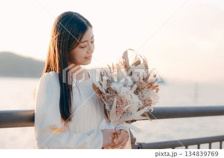 海を背景にドライフラワーを持って佇む日本人女性 海を背景にドライフラワーを持って佇む日本人女性 134839769