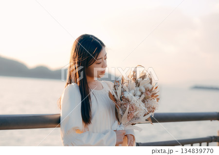 海を背景にドライフラワーを持って佇む日本人女性 海を背景にドライフラワーを持って佇む日本人女性 134839770