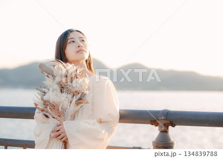 海を背景にドライフラワーを持って佇む日本人女性 海を背景にドライフラワーを持って佇む日本人女性 134839788