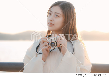 海辺でフィルムカメラを手にする日本人女性 134839833