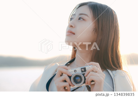 海辺でフィルムカメラを手にする日本人女性 134839835