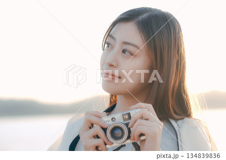 海辺でフィルムカメラを手にする日本人女性 海辺でフィルムカメラを手にする日本人女性 134839836