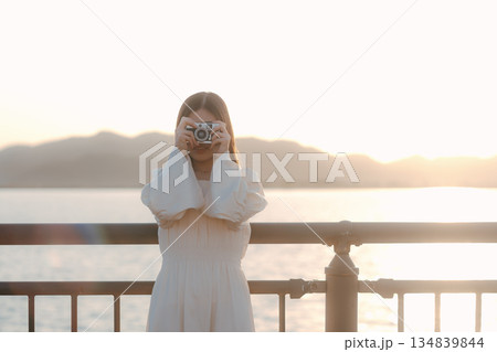 海辺でフィルムカメラを手にする日本人女性 134839844