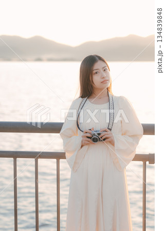 海辺でフィルムカメラを手にする日本人女性 134839848