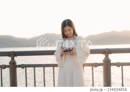 海辺でフィルムカメラを手にする日本人女性 134839858