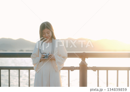 海辺でフィルムカメラを手にする日本人女性 海辺でフィルムカメラを手にする日本人女性 134839859
