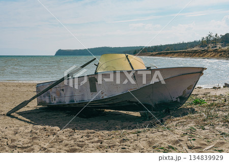 Old fishing boat with an oar on a sandy beach next to the sea Old fishing boat with an oar on a sandy beach next to the sea 134839929