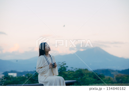 山を背景にフィルムカメラを手に佇む日本人女性 134840182
