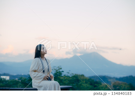 山を背景にフィルムカメラを手に佇む日本人女性 山を背景にフィルムカメラを手に佇む日本人女性 134840183