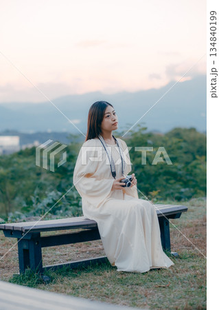 街並みを背景にフィルムカメラを手に佇む日本人女性 134840199