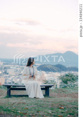 街並みを背景にフィルムカメラを手に佇む日本人女性 134840211