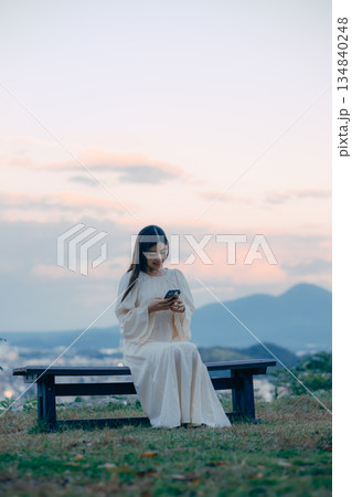 街並みを望む高台でスマートフォンを見る日本人女性 街並みを望む高台でスマートフォンを見る日本人女性 134840248