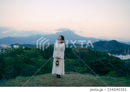 山の夕暮れにランタンを持って佇む女性 134840381