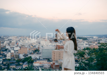 街を見下ろす高台でランタンを持つ女性 134840503