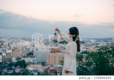 街を見下ろす高台でランタンを持つ女性 134840504