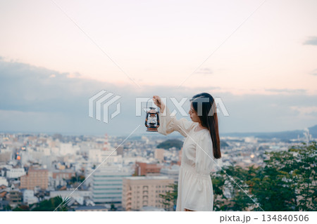 街を見下ろす高台でランタンを持つ女性 134840506