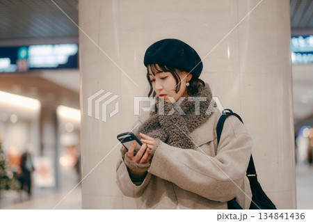 待ち合わせをしながらスマートフォンを使う30代女性 待ち合わせをしながらスマートフォンを使う30代女性 134841436