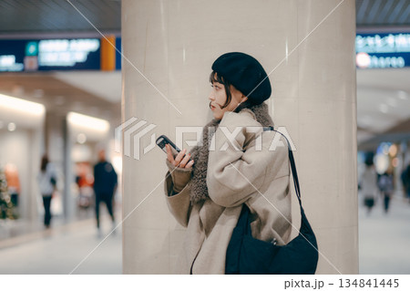 待ち合わせをしながらスマートフォンを使う30代女性 待ち合わせをしながらスマートフォンを使う30代女性 134841445