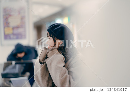 座ってスマートフォンを操作しながら待ち合わせをする30代女性 座ってスマートフォンを操作しながら待ち合わせをする30代女性 134841917
