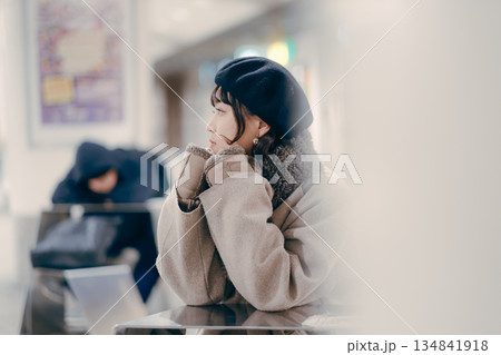 座ってスマートフォンを操作しながら待ち合わせをする30代女性 座ってスマートフォンを操作しながら待ち合わせをする30代女性 134841918
