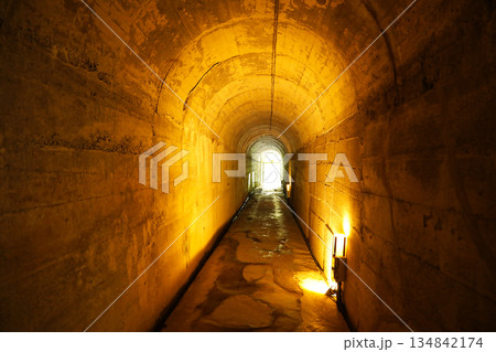暖色の照明が続く長いコンクリートトンネルと光り輝く出口の風景 134842174