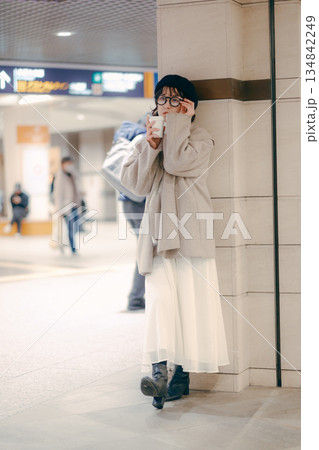 待ち合わせ中にコーヒーを飲む30代女性の全身ポートレート 待ち合わせ中にコーヒーを飲む30代女性の全身ポートレート 134842249