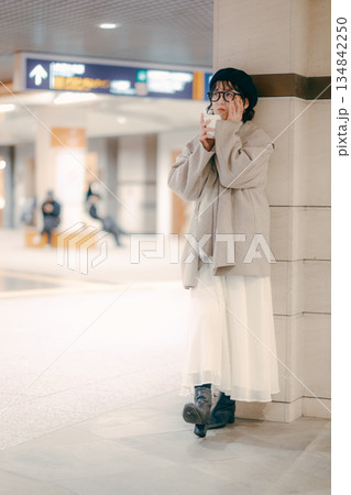 待ち合わせ中にコーヒーを飲む30代女性の全身ポートレート 134842250