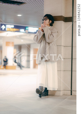待ち合わせ中にコーヒーを飲む30代女性の全身ポートレート 待ち合わせ中にコーヒーを飲む30代女性の全身ポートレート 134842252