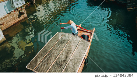 Charming boatman steering through serene waters in a traditional canoe. Zhujiajiao, Shanghai, China 134842394