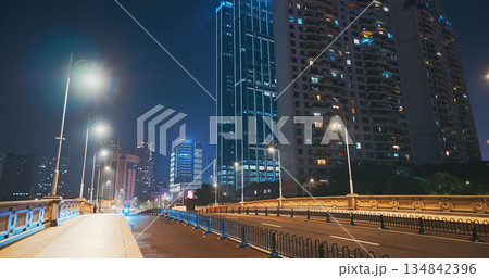 Modern City Street Filled with Skyscrapers and Moving Traffic at Night 134842396