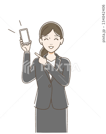 片手でスマホを持ち指をさして笑顔で話すスーツの女性 134842406