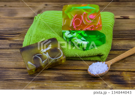 Set of handmade soap bars, sea salt and towel on wooden background. SPA concept Set of handmade soap bars, sea salt and towel on wooden background. SPA concept 134844043