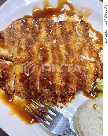 Crispy tonkatsu, a Japanese-style breaded and deep-fried pork cutlet, served with shredded cabbage and drizzled with savory sauce. A delightful balance of crunchy texture and juicy meat. 134845335