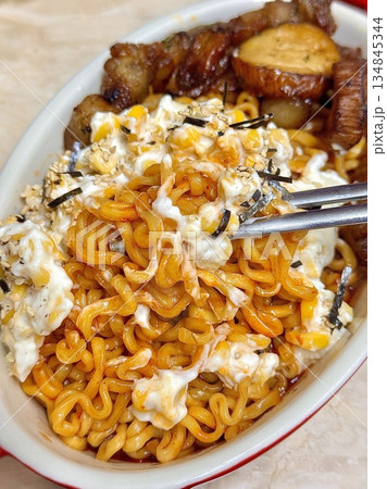 Spicy buldak ramyeon with fiery noodles paired with creamy, savory corn cheese, creating a perfect balance of heat and rich flavors in every satisfying bite. A must-try for spicy food lovers. 134845344